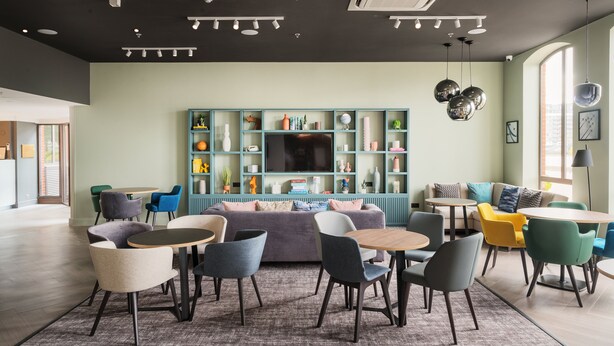 A modern living room with a large TV, a blue bookshelf, and multiple seating areas.