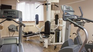 A gym with cardio machines, weight training equipment, and a treadmill.