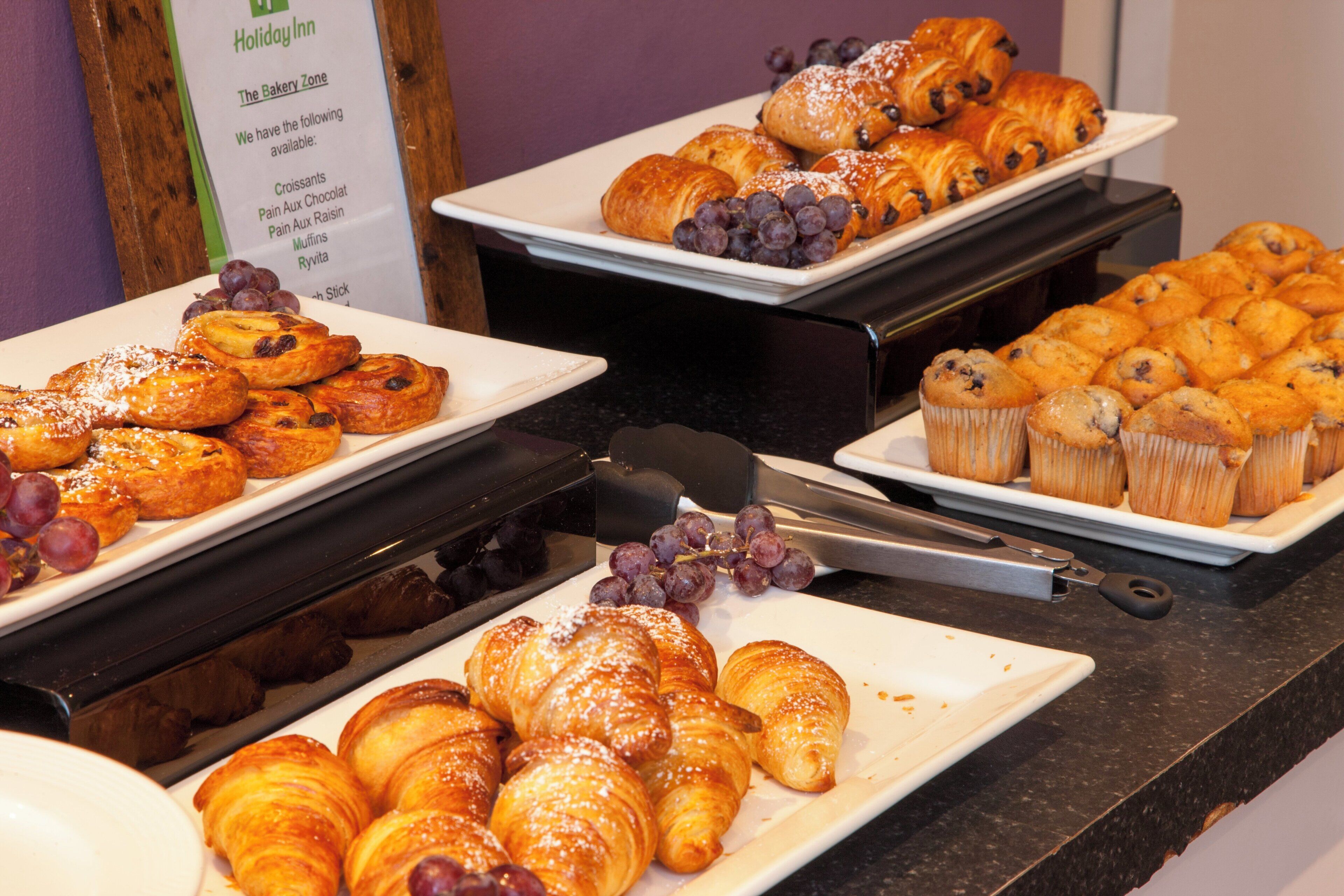A buffet with various baked goods including croissants, muffins, and pastries.