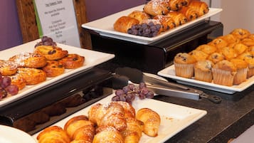 A buffet with various baked goods including croissants, muffins, and pastries.