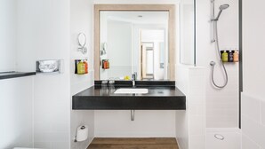 A modern bathroom with a black countertop sink, a mirror, and a shower with a handheld showerhead.
