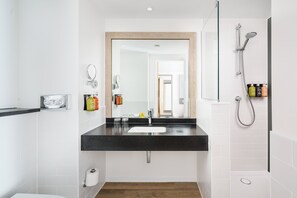 A modern bathroom with a black countertop sink, a mirror, and a shower with a handheld showerhead.