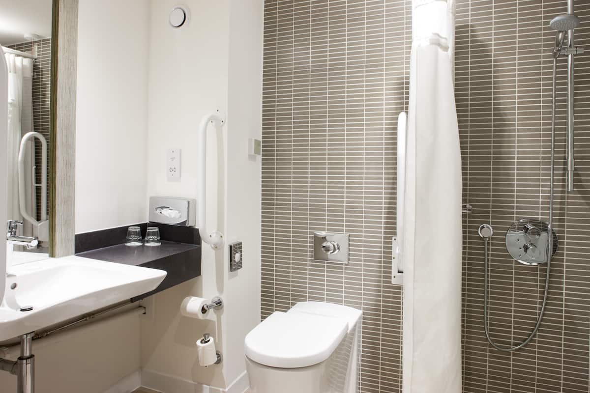 A modern bathroom with a white sink, toilet, and shower.