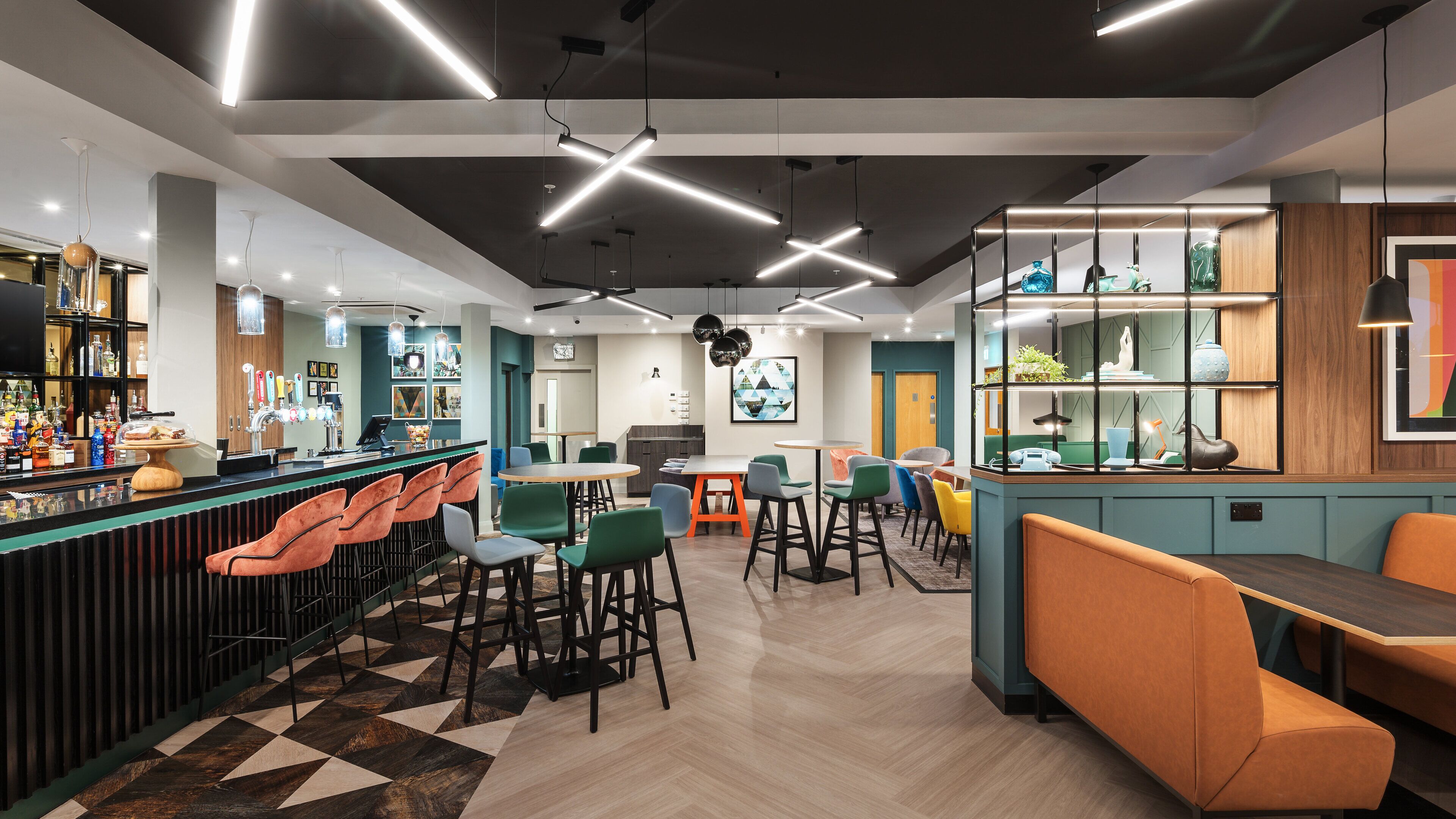 A modern bar area with a counter, bar stools, and a variety of seating options including tables and chairs.