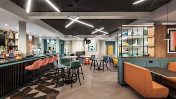 A modern bar area with a counter, bar stools, and a variety of seating options including tables and chairs.