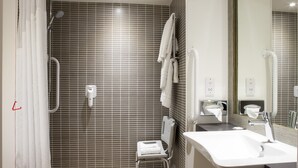 A modern bathroom with a shower, a toilet, a sink, and a mirror.