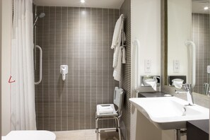 A modern bathroom with a shower, a toilet, a sink, and a mirror.