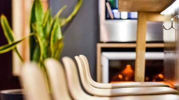 A modern kitchen with a stainless steel refrigerator, a wooden cabinet, and a plant in a white vase.