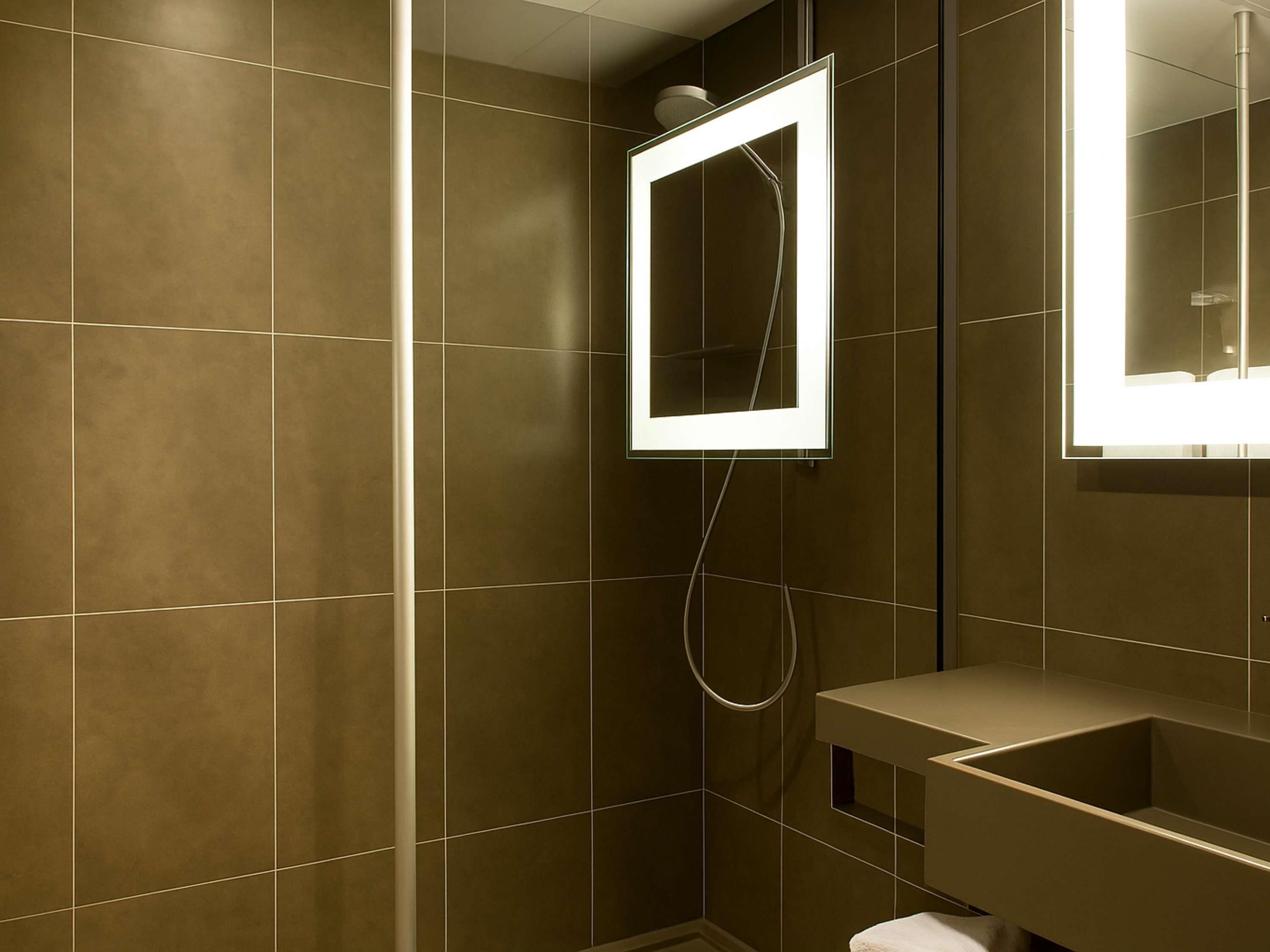 A bathroom with a shower, a mirror, and a sink.