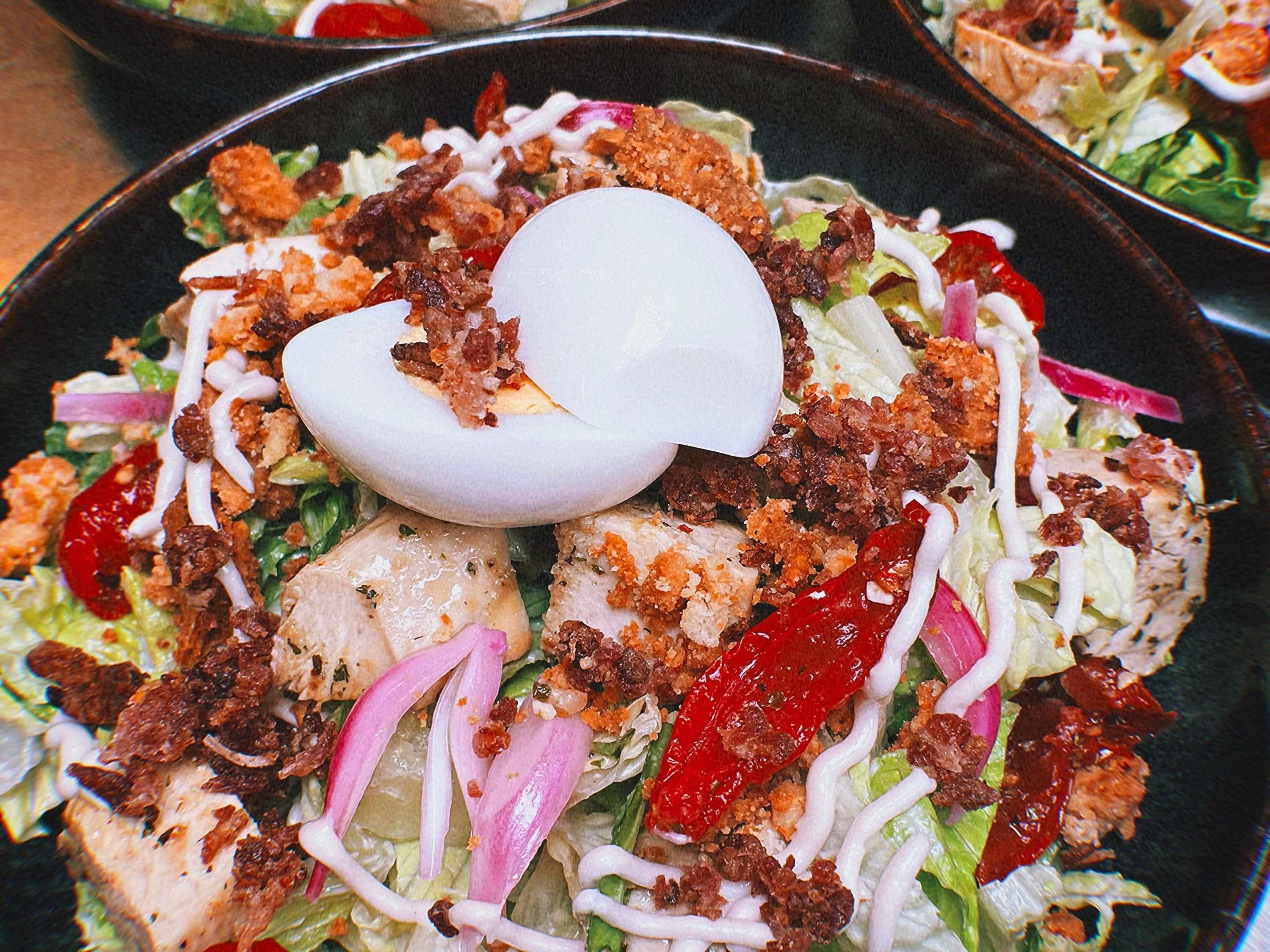 Une salade garnie de divers ingrédients, avec un œuf dur sur le dessus.