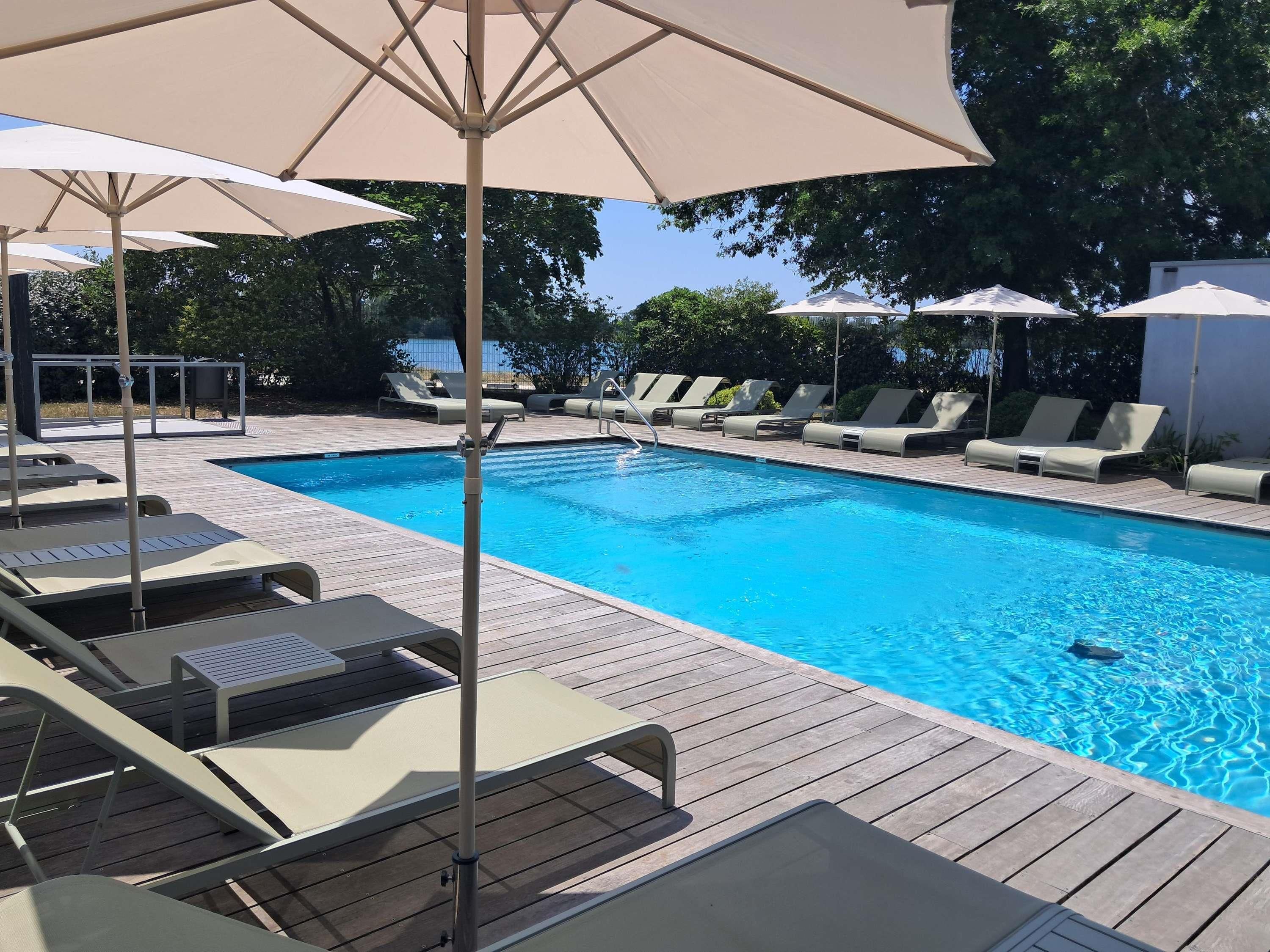 Une piscine avec des chaises longues et des parasols.