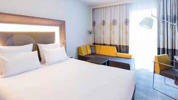 Ett hotellrum med en stor säng, en soffa, ett litet bord och en stol.