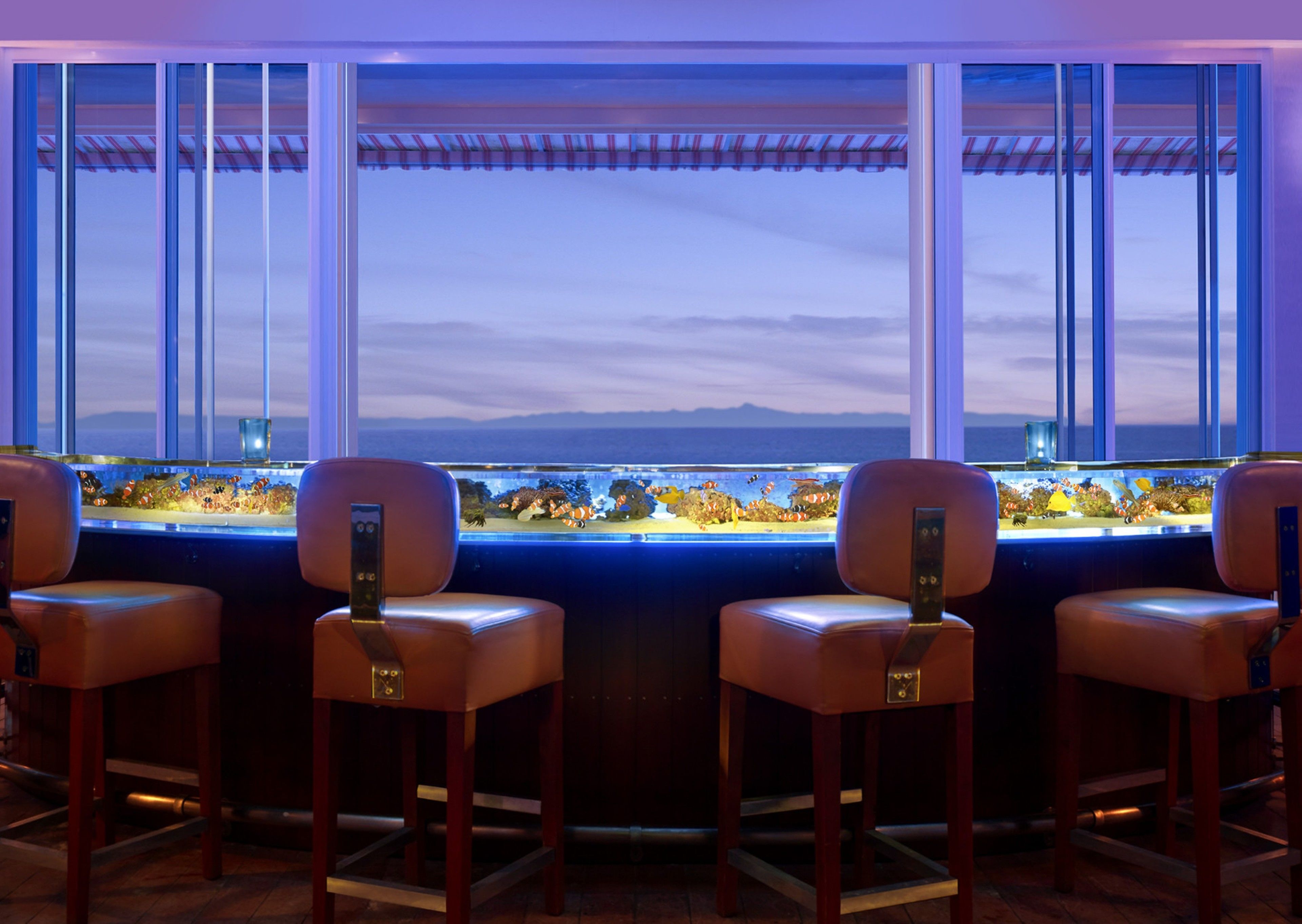 A bar area with four leather chairs and a large aquarium window.