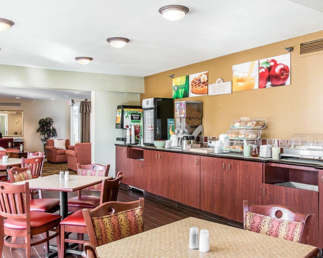 A hotel dining area with a counter, seating, and a refrigerator.