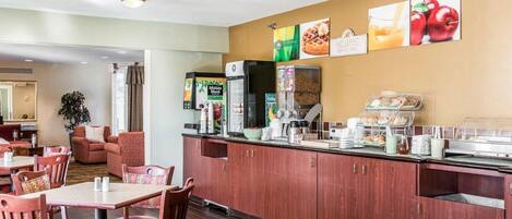 A hotel dining area with a counter, seating, and a refrigerator.