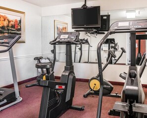 A gym with stationary bikes, treadmills, and a TV screen.