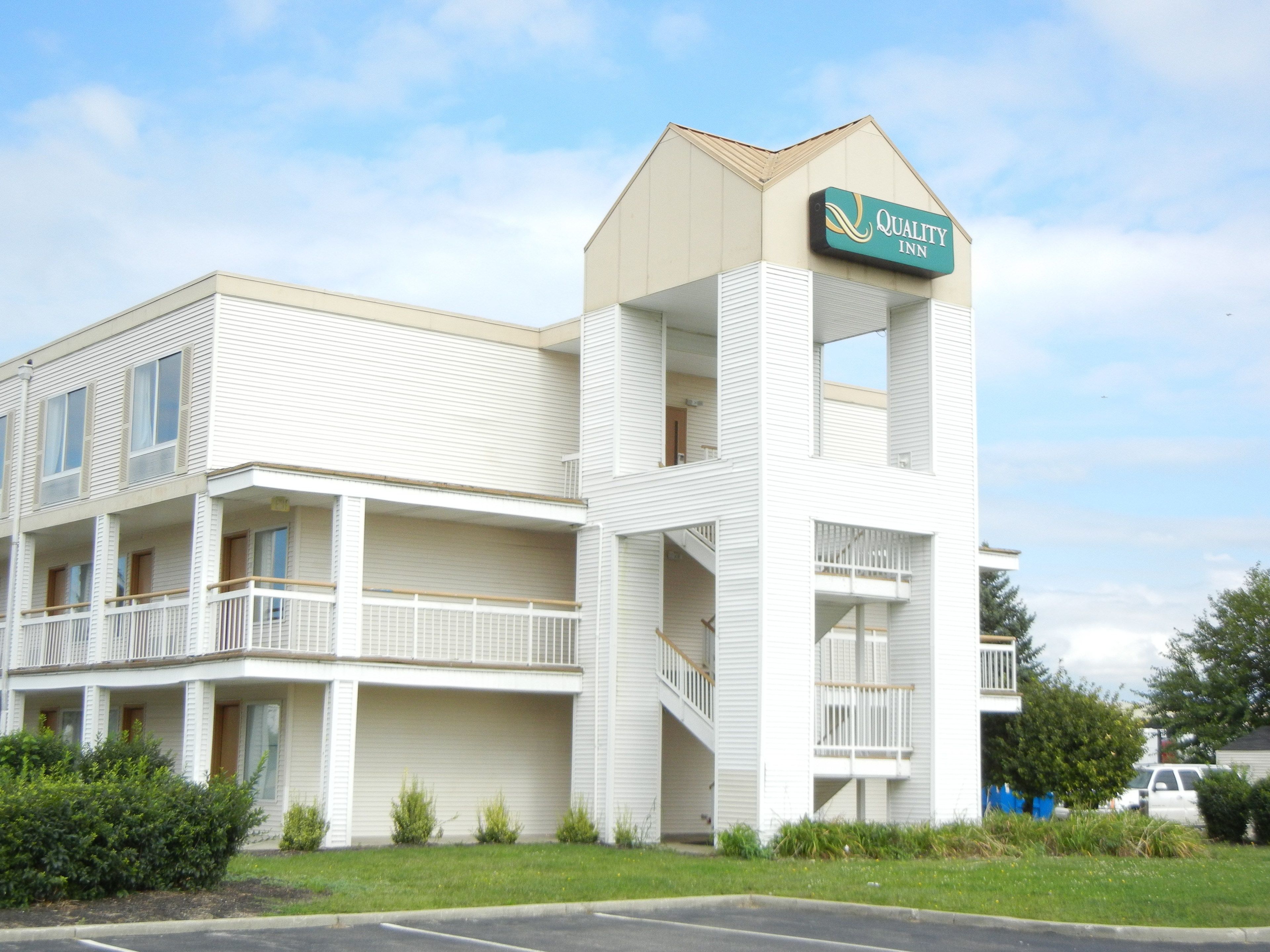 A two-story building with a sign for Quality Inn. It has balconies on the second floor and a staircase leading to the entrance.