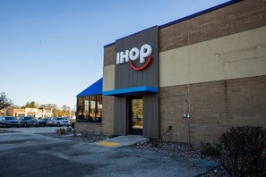 A building with a sign reading "IHOP" and a parking lot with several cars. - Holiday Inn Brookfield - ​​Milwaukee by IHG (Brookfield)