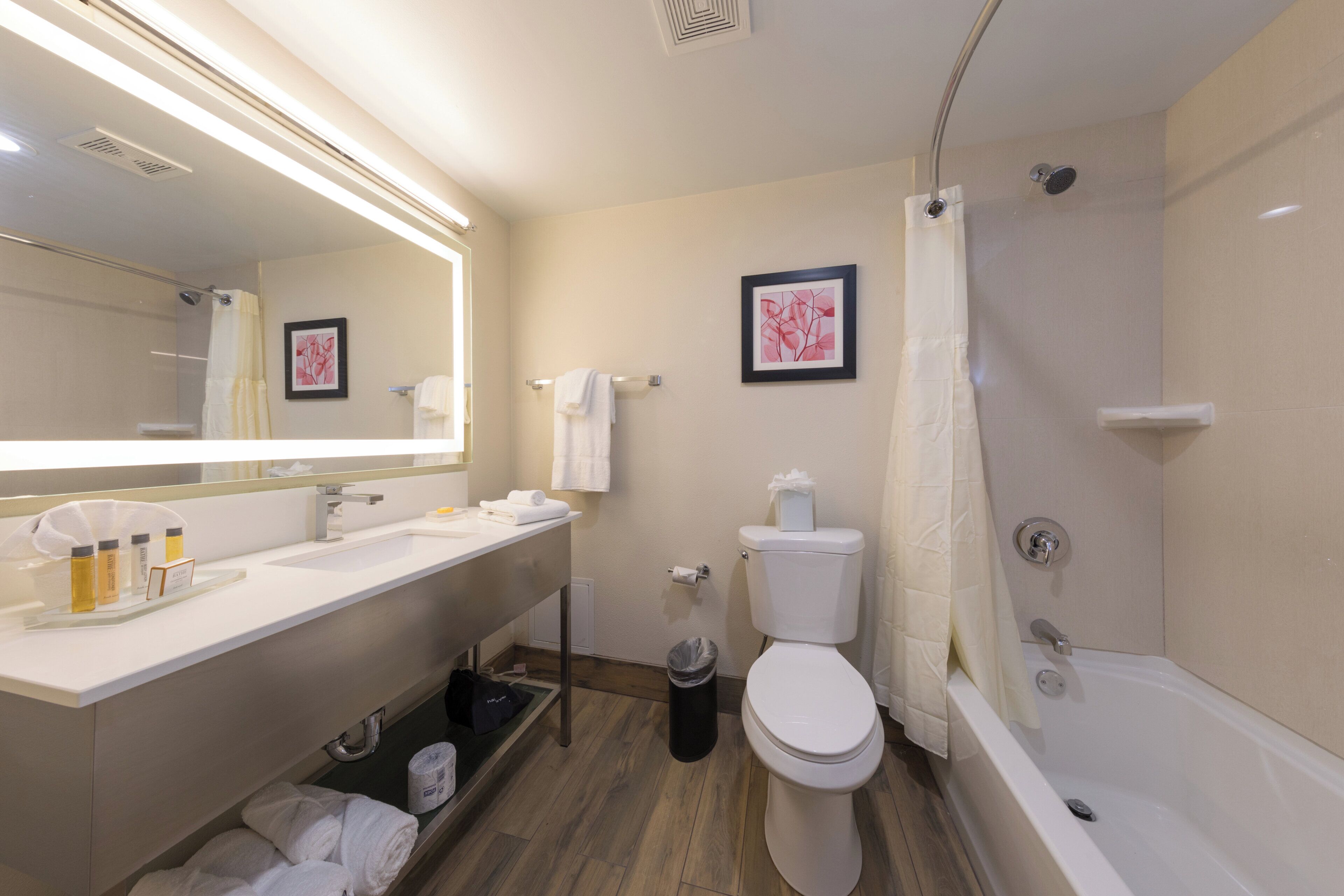 A modern bathroom with a white sink, mirror, toilet, and bathtub.