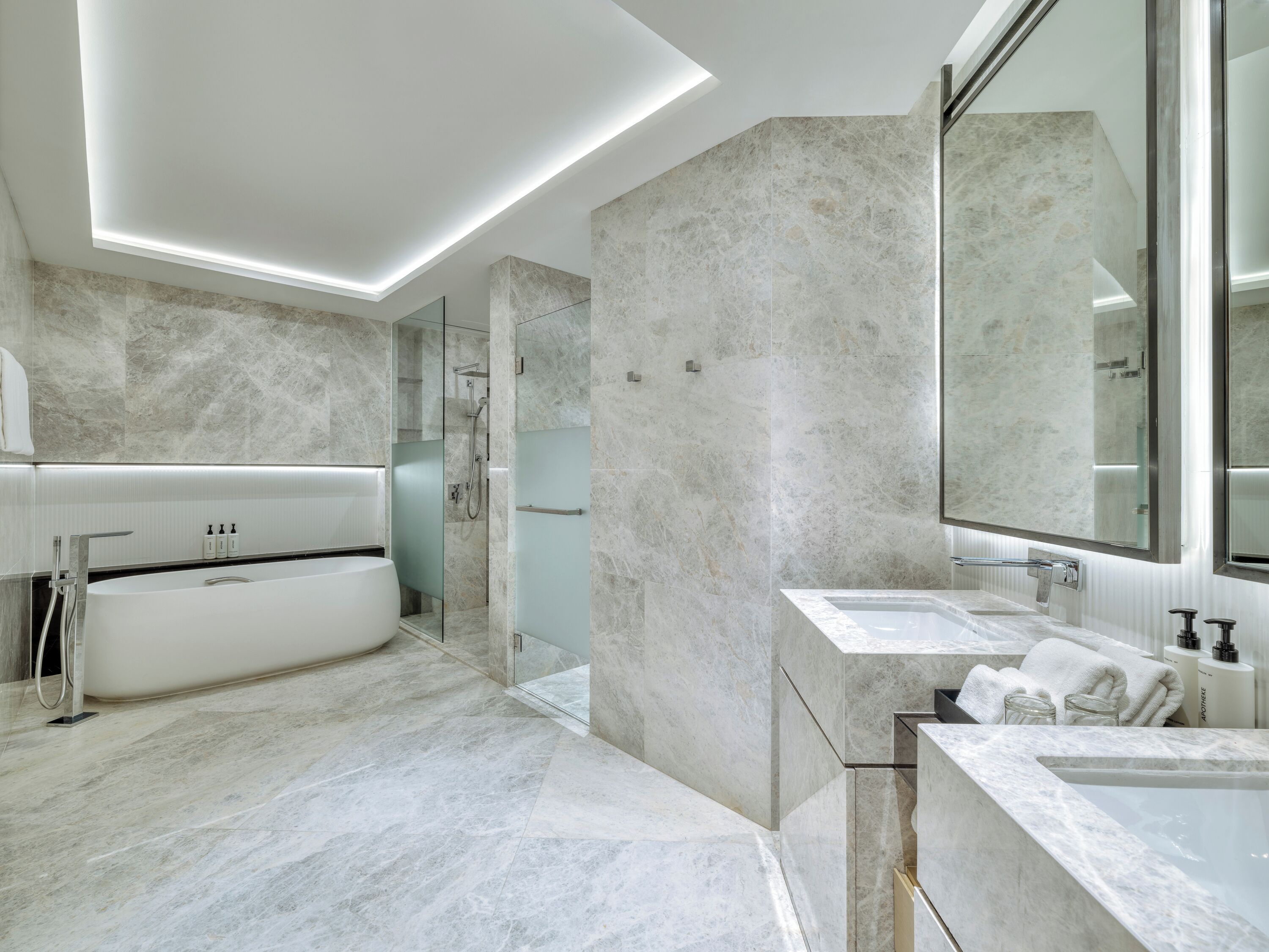 A modern bathroom with a freestanding bathtub, a glass-enclosed shower, and a vanity with a large mirror.