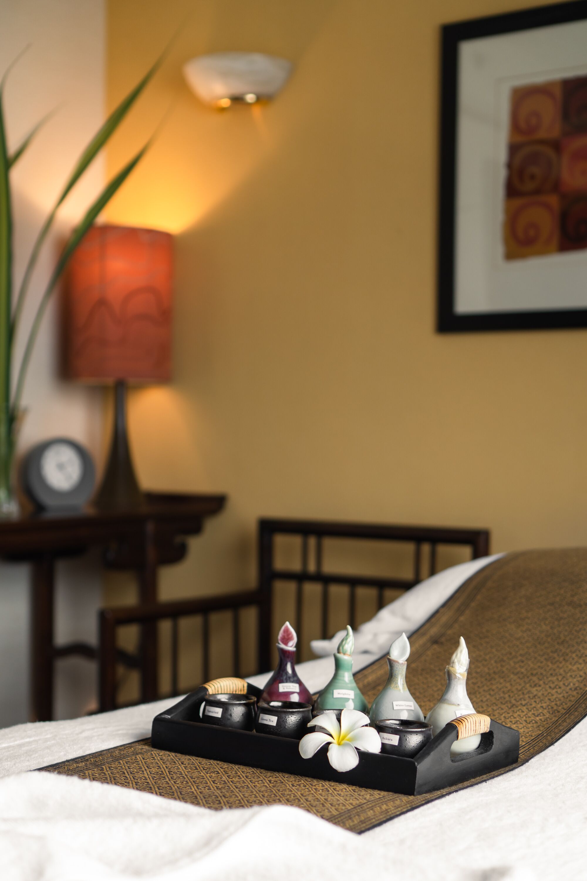 Una bandeja ordenada con velas y una flor sobre una cama en una habitación de hotel.
