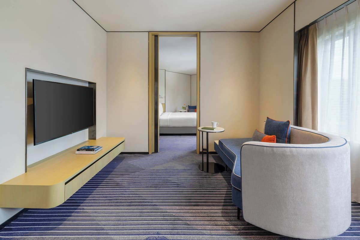 Habitación de hotel con televisión de pantalla plana, un sofá, una mesita y una cama.