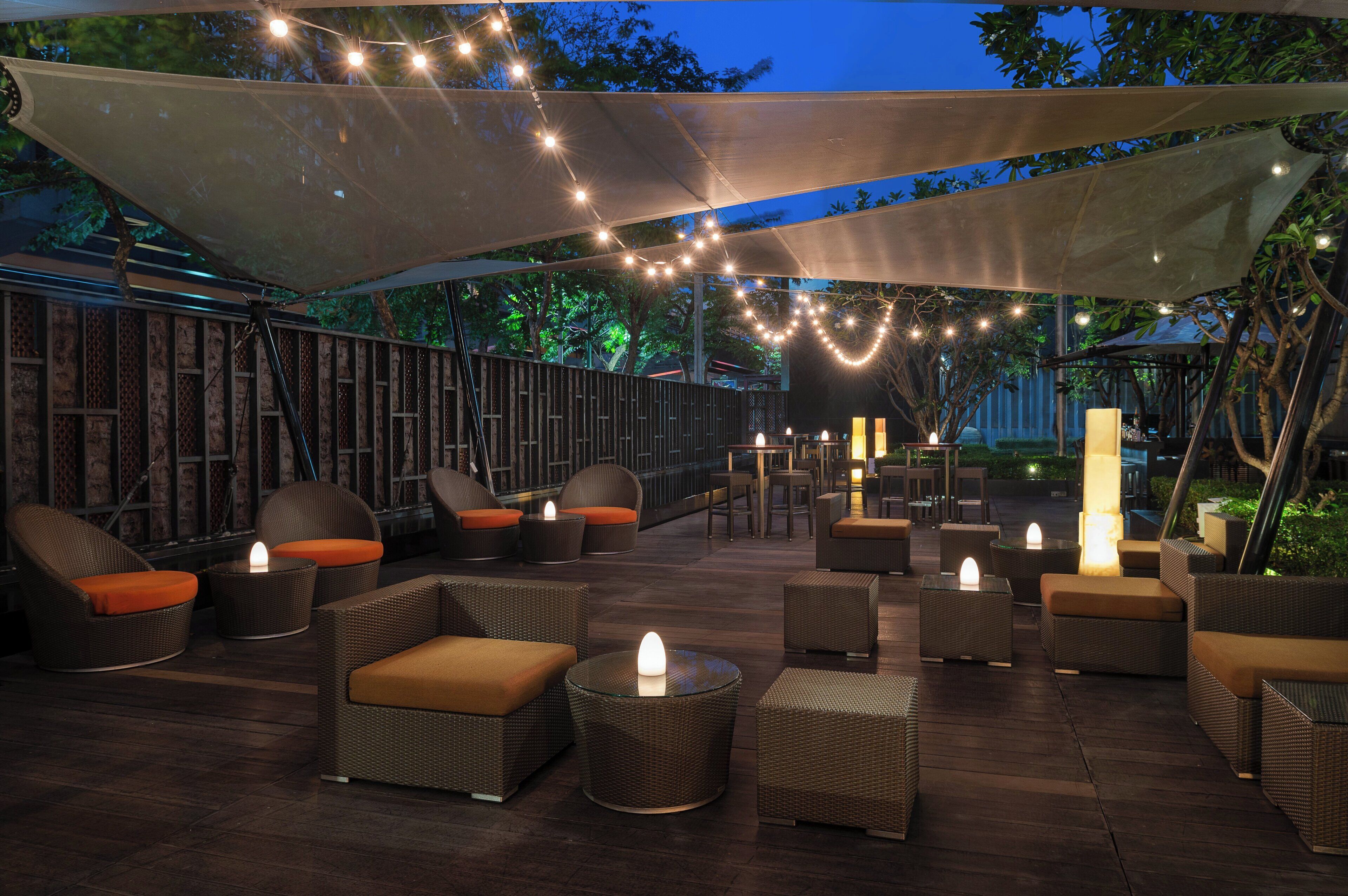 An outdoor seating area with wicker furniture and string lights.