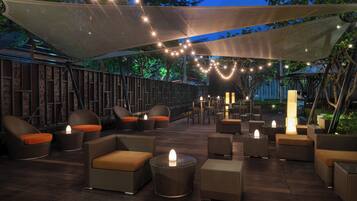 An outdoor seating area with wicker furniture and string lights.
