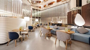 A modern interior with a mix of seating areas, including round tables and sofas, and a decorative wall with vertical elements. - Crowne Plaza Bangkok Lumpini Park by IHG (Bangkok)