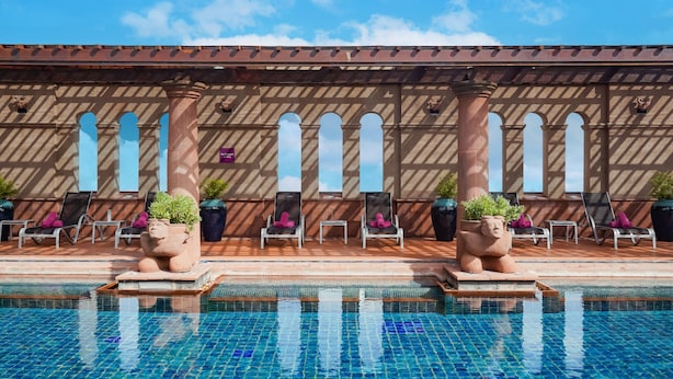 A pool area with tiled flooring, lounge chairs, and potted plants. - Crowne Plaza Bangkok Lumpini Park by IHG (Bangkok)