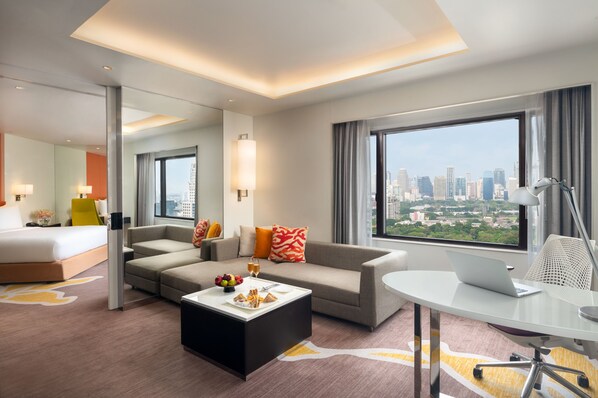 A modern hotel room with a bed, sofa, dining table, and a laptop on a desk. - Crowne Plaza Bangkok Lumpini Park by IHG (Bangkok)