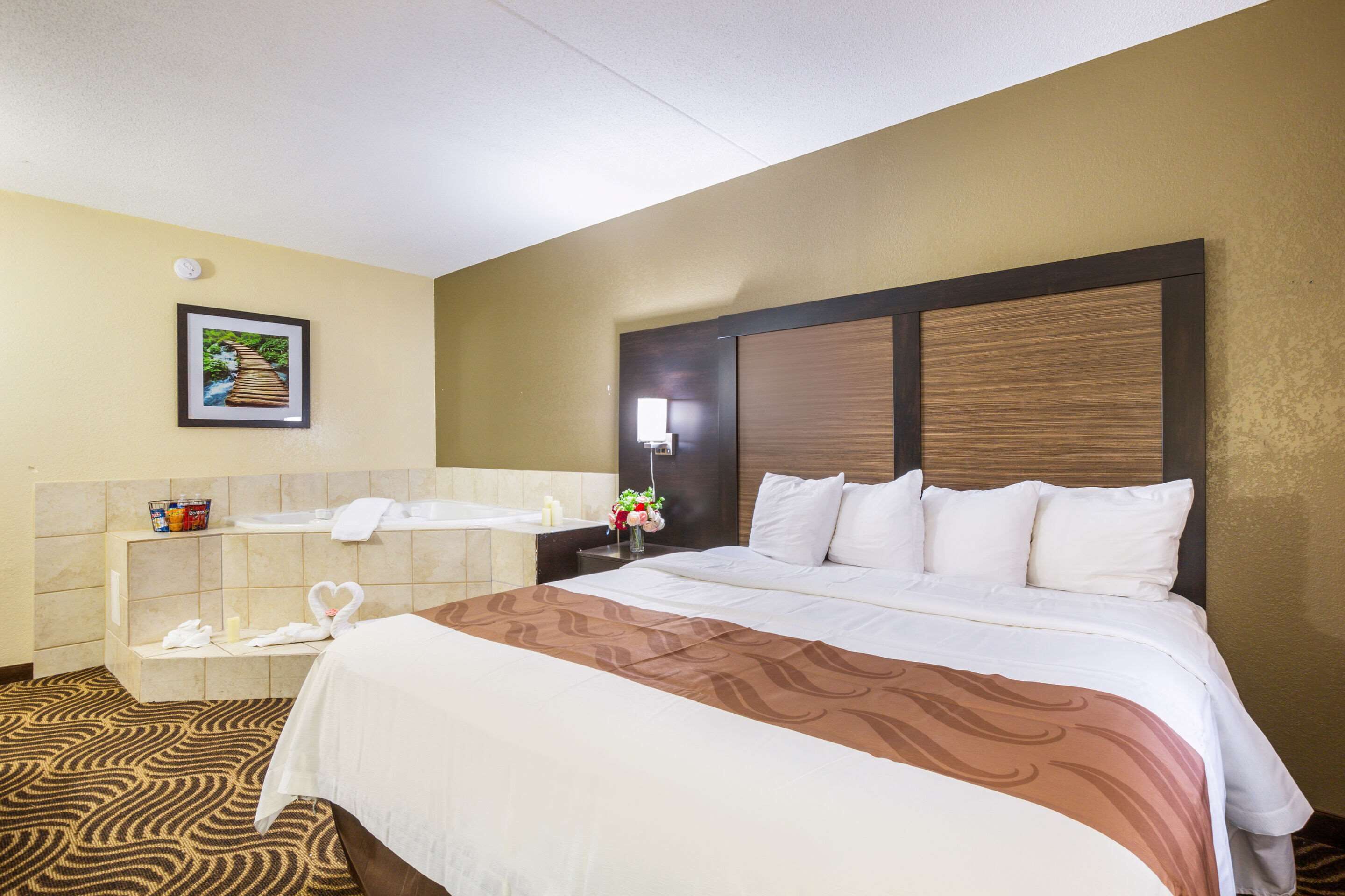 Habitación de hotel con una cama grande, un baño con bañera y un cuadro de un puente en la pared.