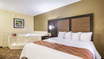 A hotel room with a large bed, a bathroom with a bathtub, and a picture of a bridge on the wall.