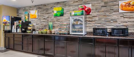 A breakfast bar with a stone wall backdrop, a refrigerator, and a microwave.
