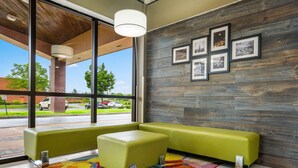A modern lobby with a large window, a colorful rug, and a wooden wall with framed pictures. - Quality Inn & Suites Florence - Cincinnati South (Florence)