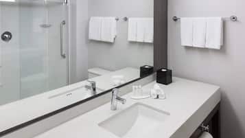 Un baño moderno con un espejo grande, un lavamanos y una zona de ducha.