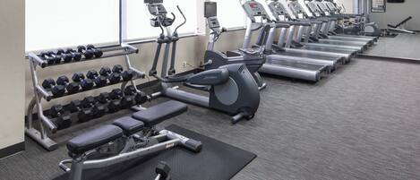 A gym with treadmills, elliptical machines, and dumbbells.