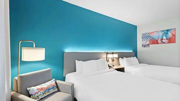 Habitación de hotel con dos camas, una silla, una mesita de noche, una lámpara y una obra de arte en la pared.