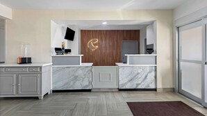 Un'area reception moderna con banconi in marmo, una parete decorativa in legno e un grande schermo.