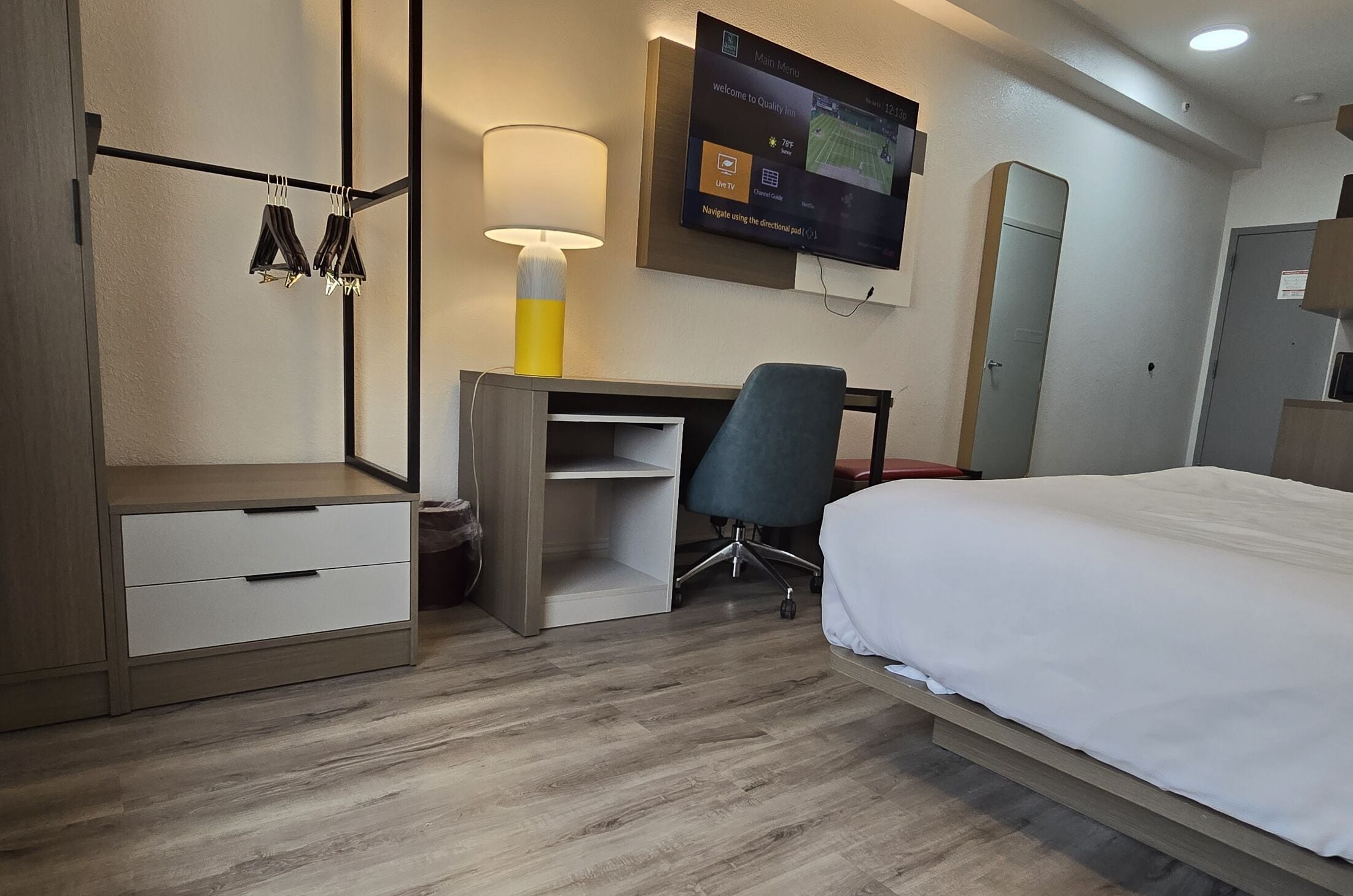 A hotel room with a bed, desk, chair, and TV mounted on the wall.