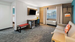 Una camera d'hotel con scrivania, sedia, divano e televisore a parete.