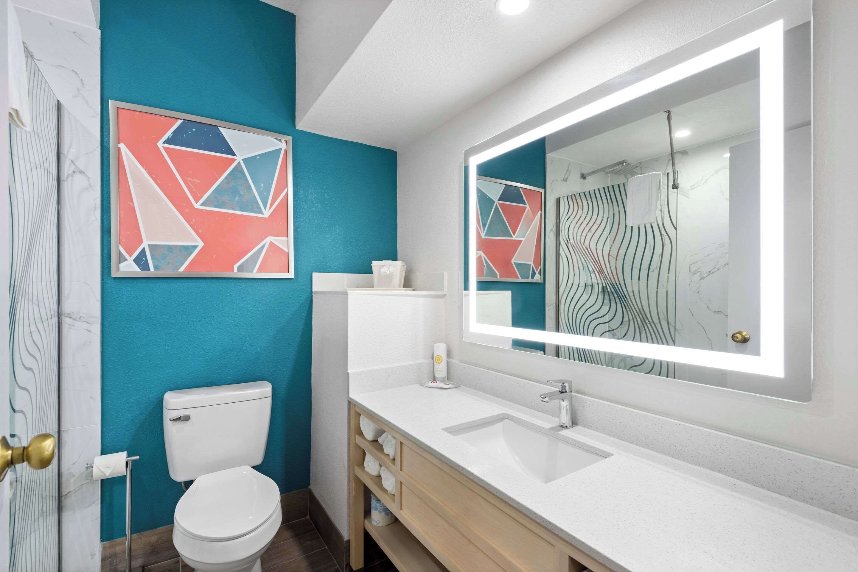 A modern bathroom with a white sink, a large mirror, and a toilet.