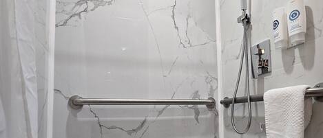 Une salle de bain avec un mur en marbre, une douche, un porte-serviettes et un sèche-mains.