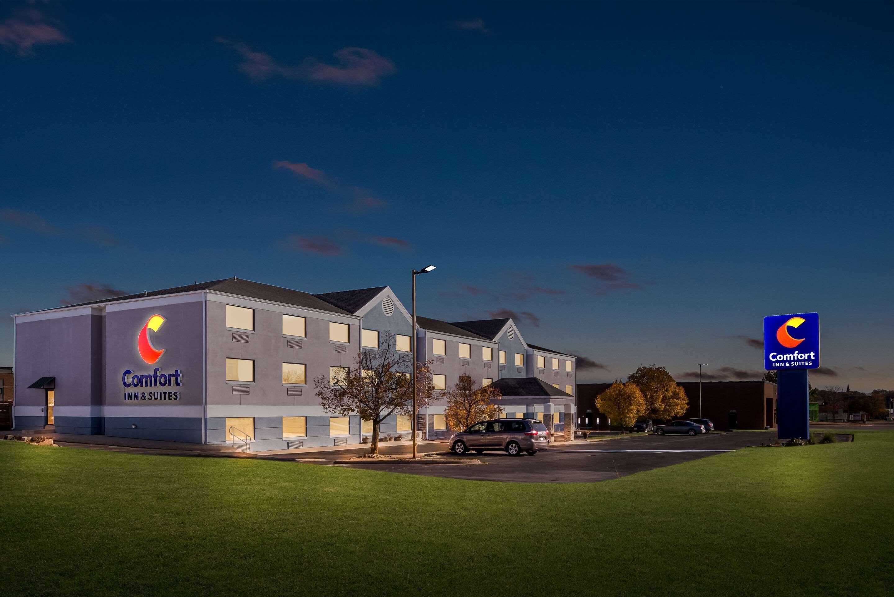A Comfort Inn & Suites hotel with a modern design, featuring a large sign and a well-maintained lawn.
