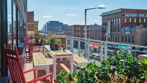 A rooftop terrace with red chairs, a wooden table, and potted plants. - Graduate by Hilton Lincoln (Lincoln)