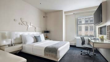 A modern hotel room with a large bed, a desk, and a TV.