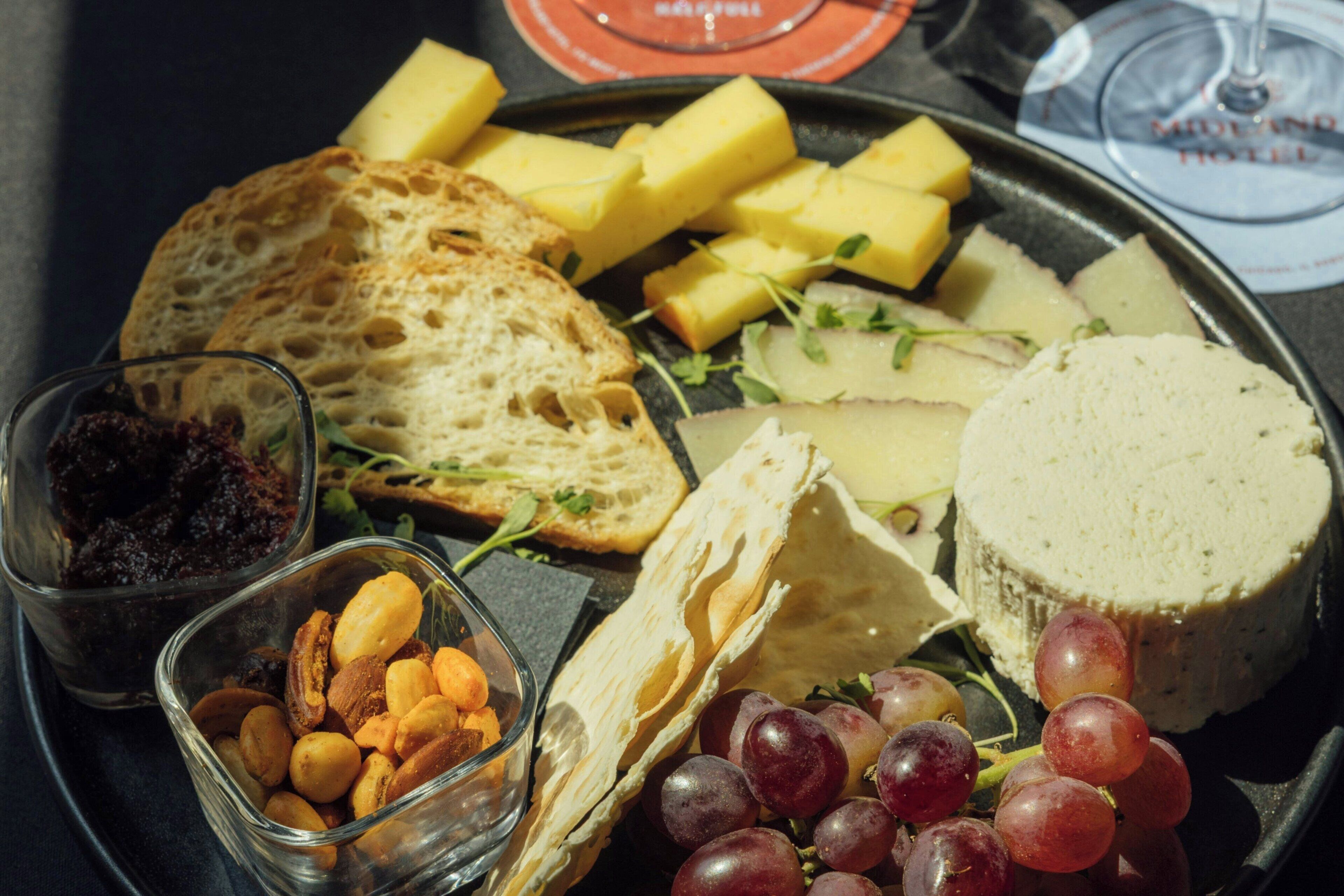 A charcuterie board with various cheeses, fruits, nuts, and bread.