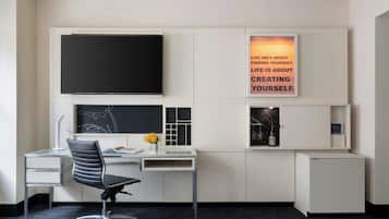A modern office desk with a flat-screen TV, a computer, and a chair.
