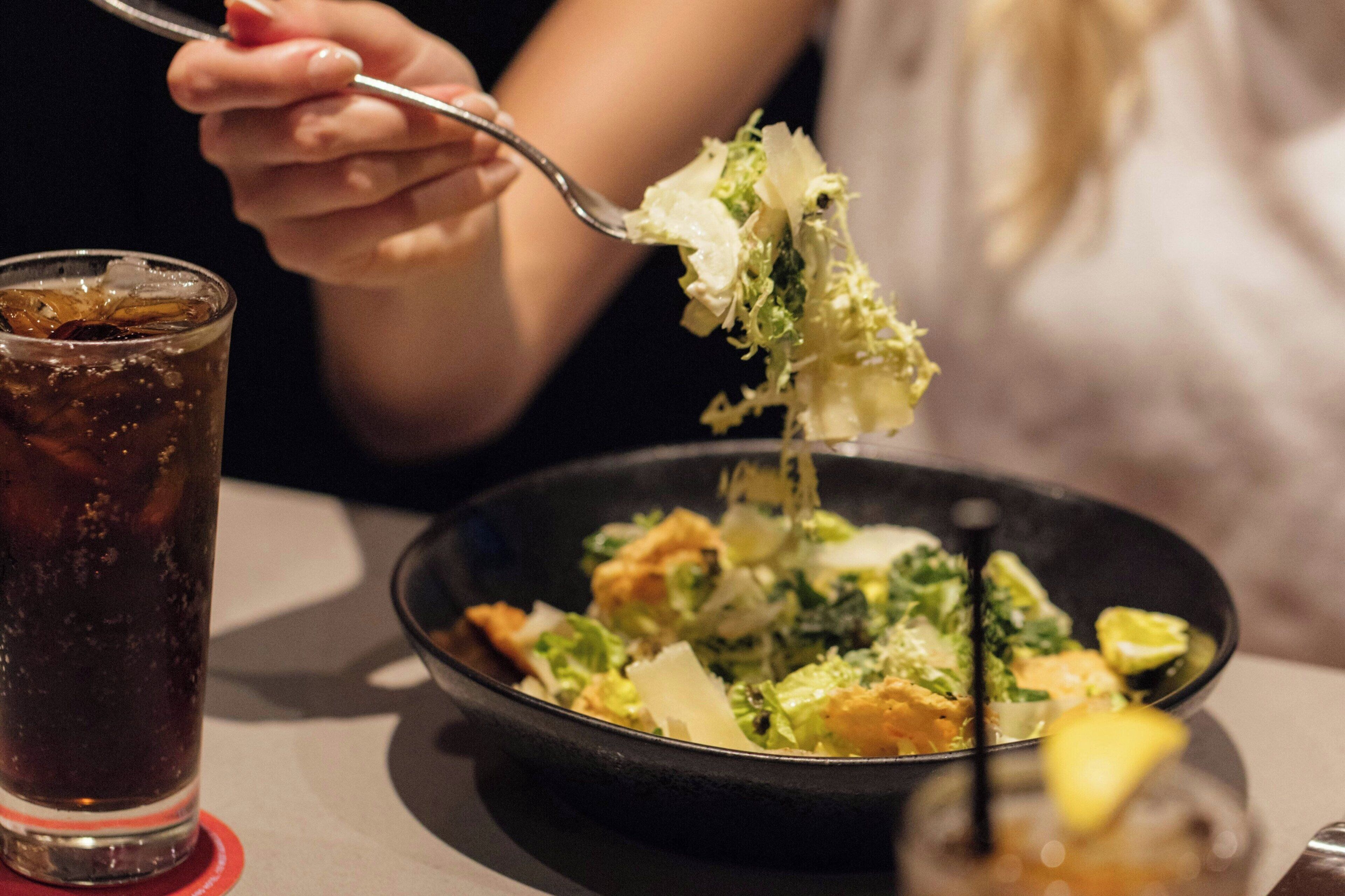 A person eating a salad with a fork.