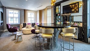 Una sala de estar moderna con una mesa de comedor redonda, taburetes de bar, un sillón púrpura y un sofá con cojines.